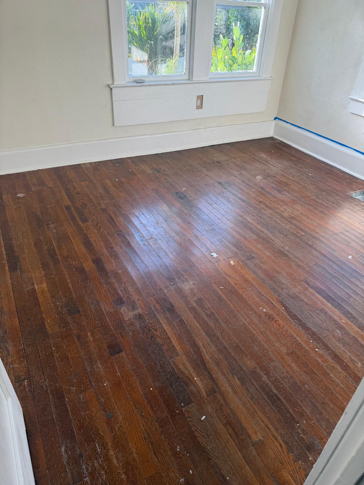 Worn dark hardwood floor before restoration