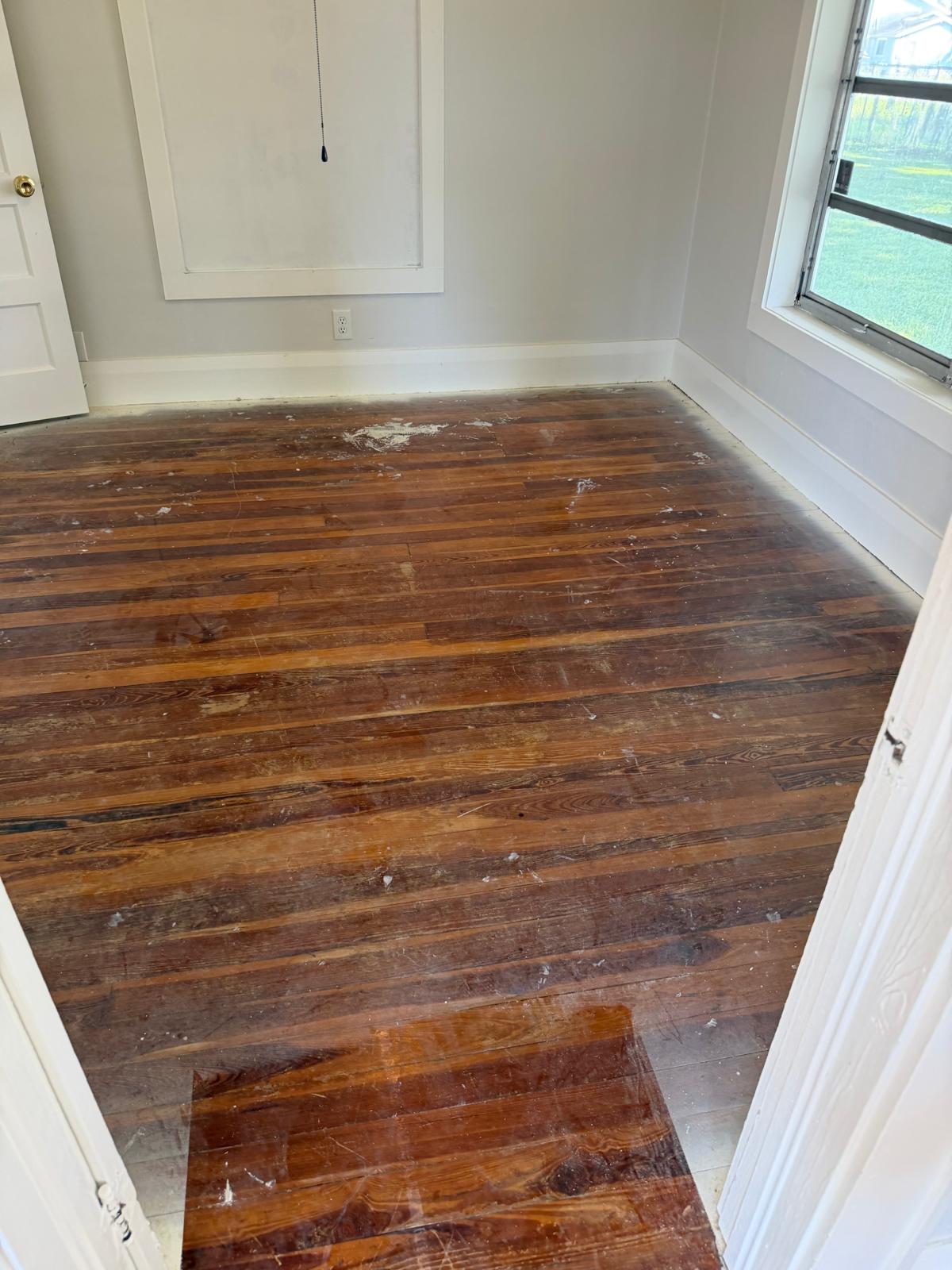 Worn, scratched hardwood floor with damaged finish before restoration
